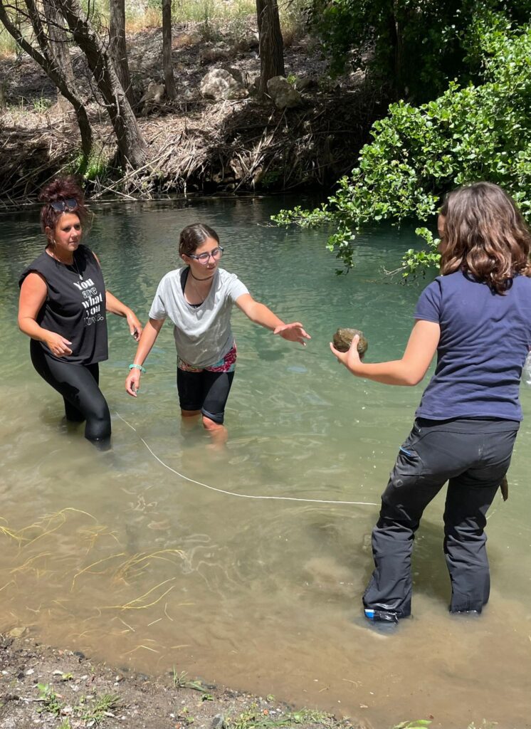 students helping each other out of natural pool in mountains