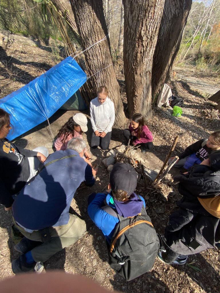 group of teenage students learning to build a fire