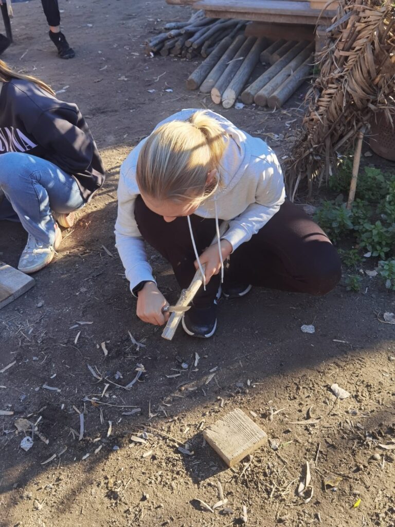 young girl cutting kindling for a campfire
